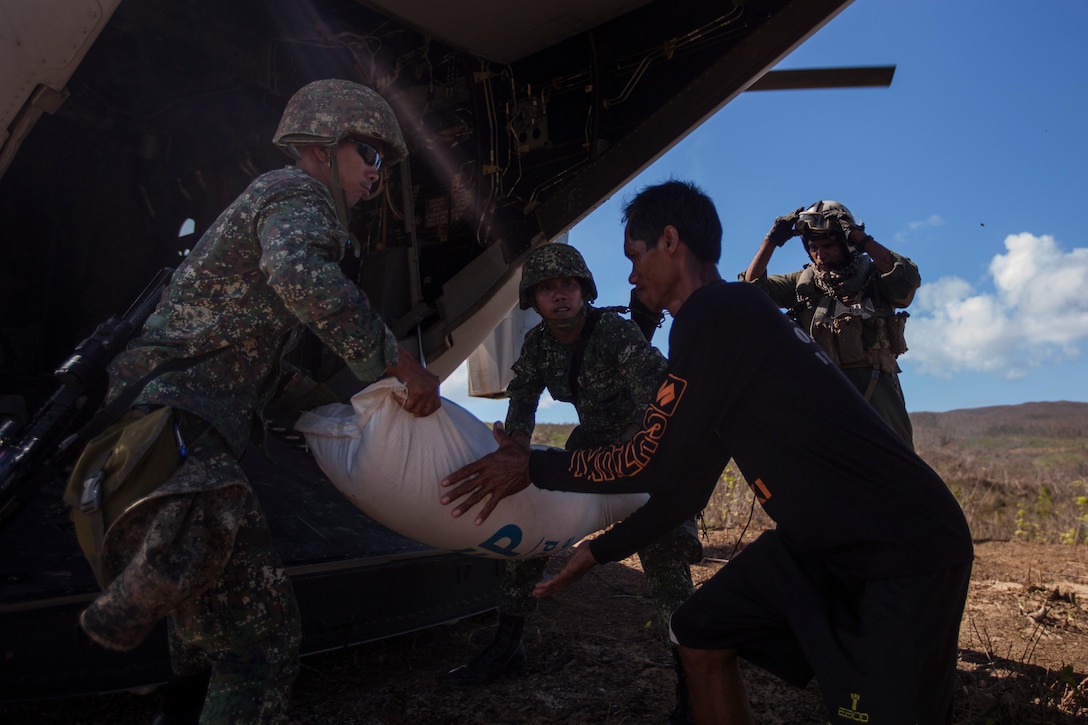 Philippine Marines pass a 110 lbs. bag of rice to a Filipino volunteer from the ramp of an MV-22 Osprey with Marine Medium Tiltrotor Squadron-265, 31st Marine Expeditionary Unit (MEU), during a supply drop-off at a village here, Nov. 25. The combined Philippine and international effort delivered more than 79,000 lbs. of rice and high-energy biscuits to eight island villages. The 31st MEU, deployed with 3D Marine Expeditionary Brigade, in support of Joint Task Force 505, is currently supporting the government of the Philippines during Operation Damayan by assisting with disaster relief efforts in areas affected by Super Typhoon Haiyan/Yolanda. 