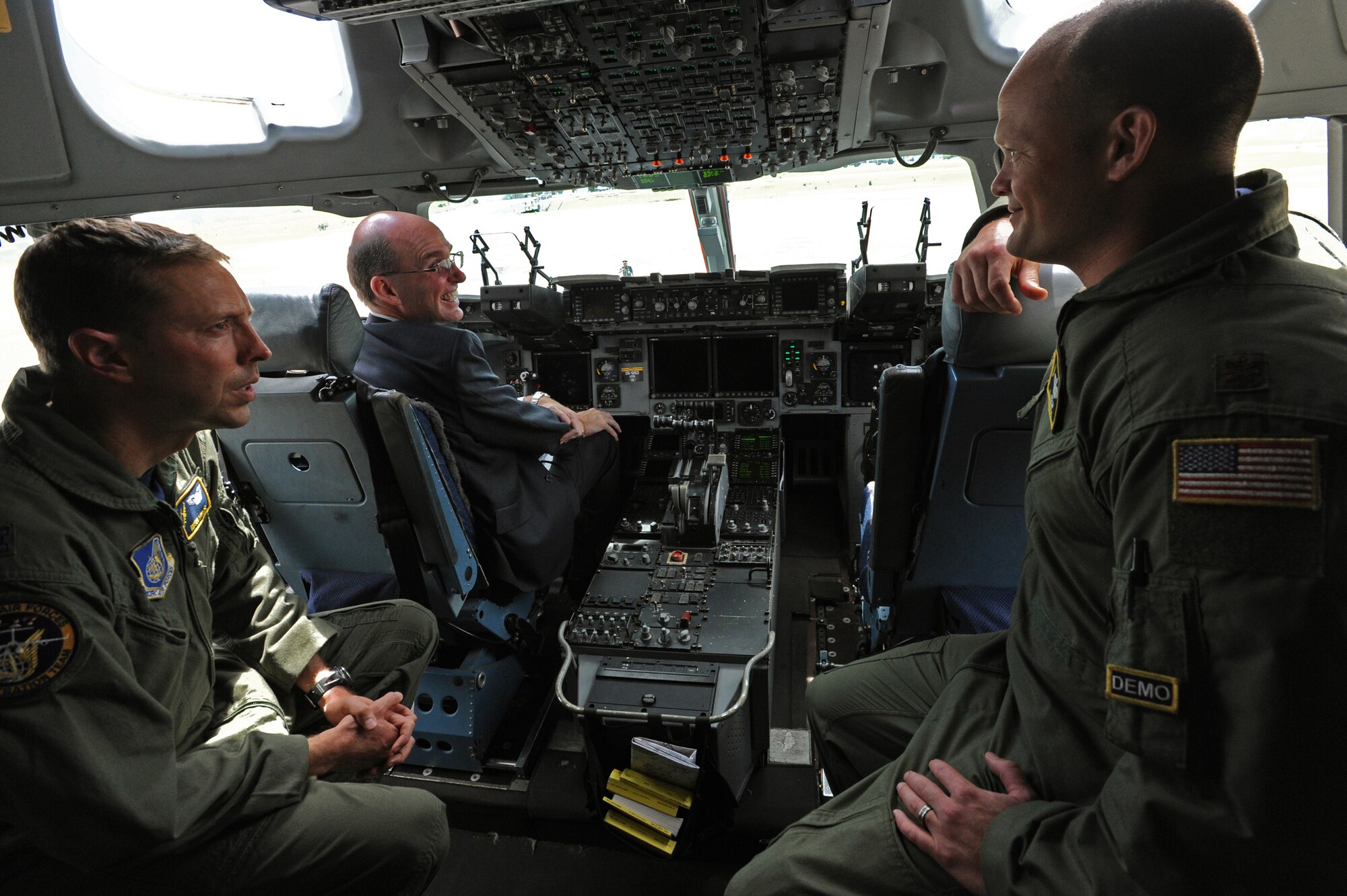Pacific Air Forces demonstration team members Capt. Rush Taylor, demo safety ground control officer, left, and Maj. Chris Ross, demo copilot, right, shows U.S. Ambassador to Brunei Daniel L. Shields, center, his way around the cockpit of a C-17 Globemaster III at Rimba Air Base during the 4th biennial Brunei Darussalam International Defense Exhibition, Dec. 3, 2013. JBPPH personnel will be showcasing the C-17 through static displays and aerial demonstrations during BRIDEX. The exhibition is an opportunity for networking and sharing technology with regional partners and allies, building strong multilateral relationships, increased cooperation and enhanced preparedness for disasters and other contingency operations. (U.S. Air Force photo/Master Sgt. Jerome S. Tayborn)