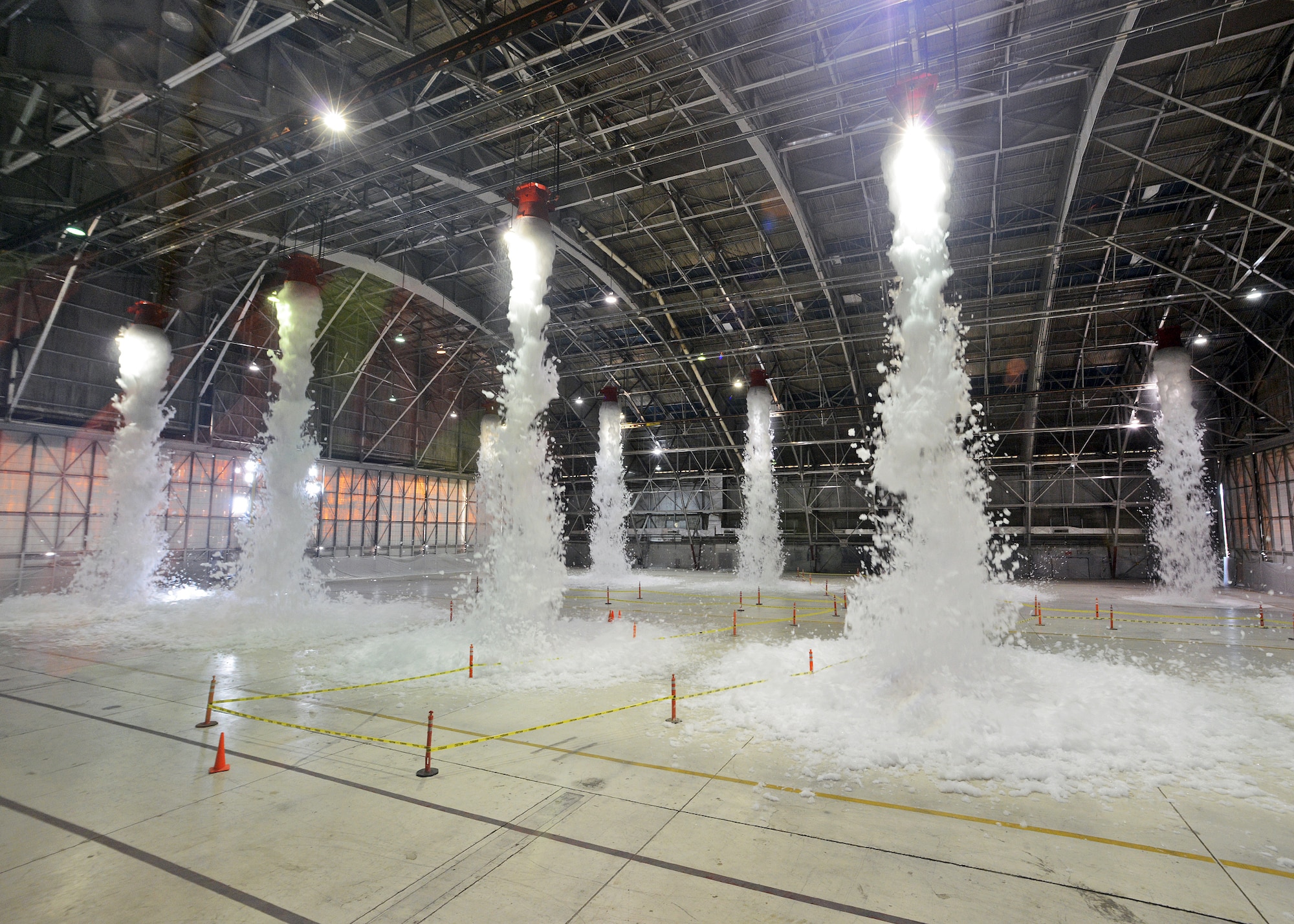 The interior of Hangar 1210 was the site of the base’s most recent emergency scenario exercise that occurred Nov. 26. The hangar, which has 10 large capacity and 2 small capacity foam generators, released approximately 110 gallons of two percent Ansul Jet-Ex foam concentrate that is part of the newly-installed fire suppression system. The foam is detergent-based with additives to keep it stable and keep it from freezing. The purpose of the exercise was so Exercise Evaluation Team members could assess how on-base emergency response personnel gain and maintain control of a site after a fire suppression system discharge incident has occurred. (U.S. Air Force photo by Jet Fabara)