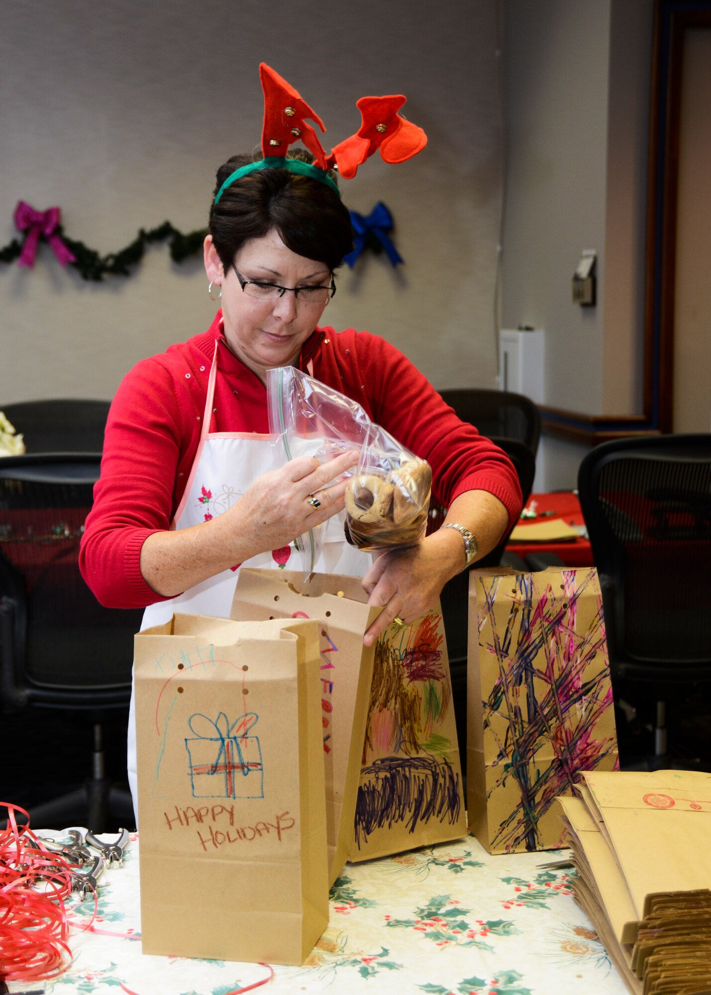 Susan Hoff, 412th Mission Support Group, packs the assorted cookies into paper bags donated by the Commissary. (U.S. Air Force photo by Rebecca Amber)