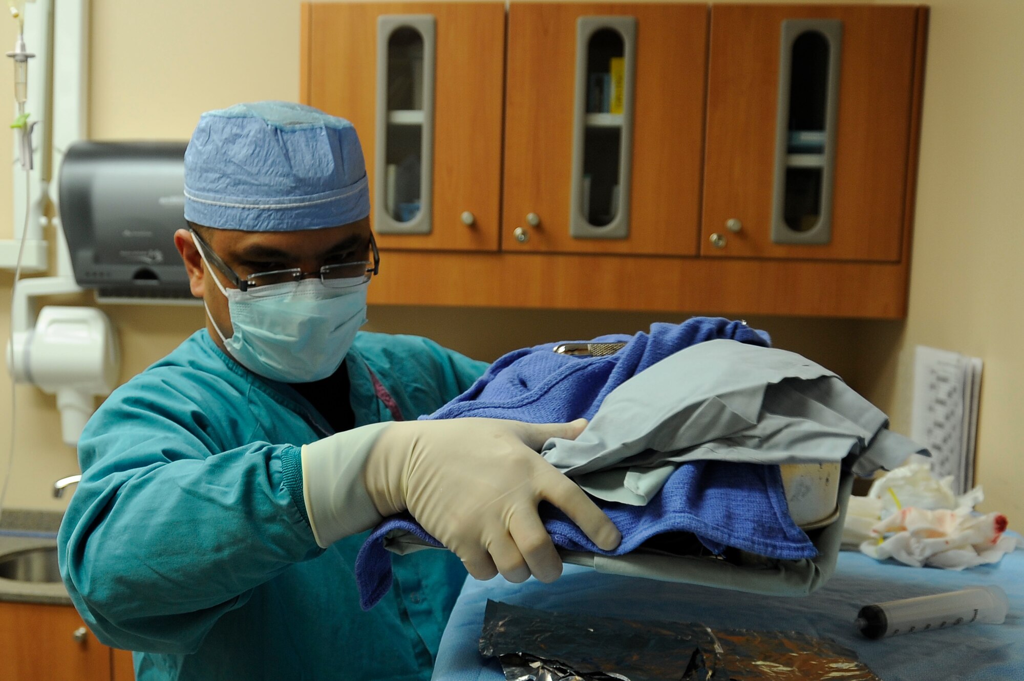 Raymond Estrella, 99th Dental Squadron dental assistant, cleans up after an oral surgery Dec. 2, 2013, at Nellis Air Force Base, Nev. Proper cleaning and disposal of equipment are used to reduce the chance of infections forming in patients after a procedure. (U.S. Air Force photo by Airman 1st Class Timothy Young)