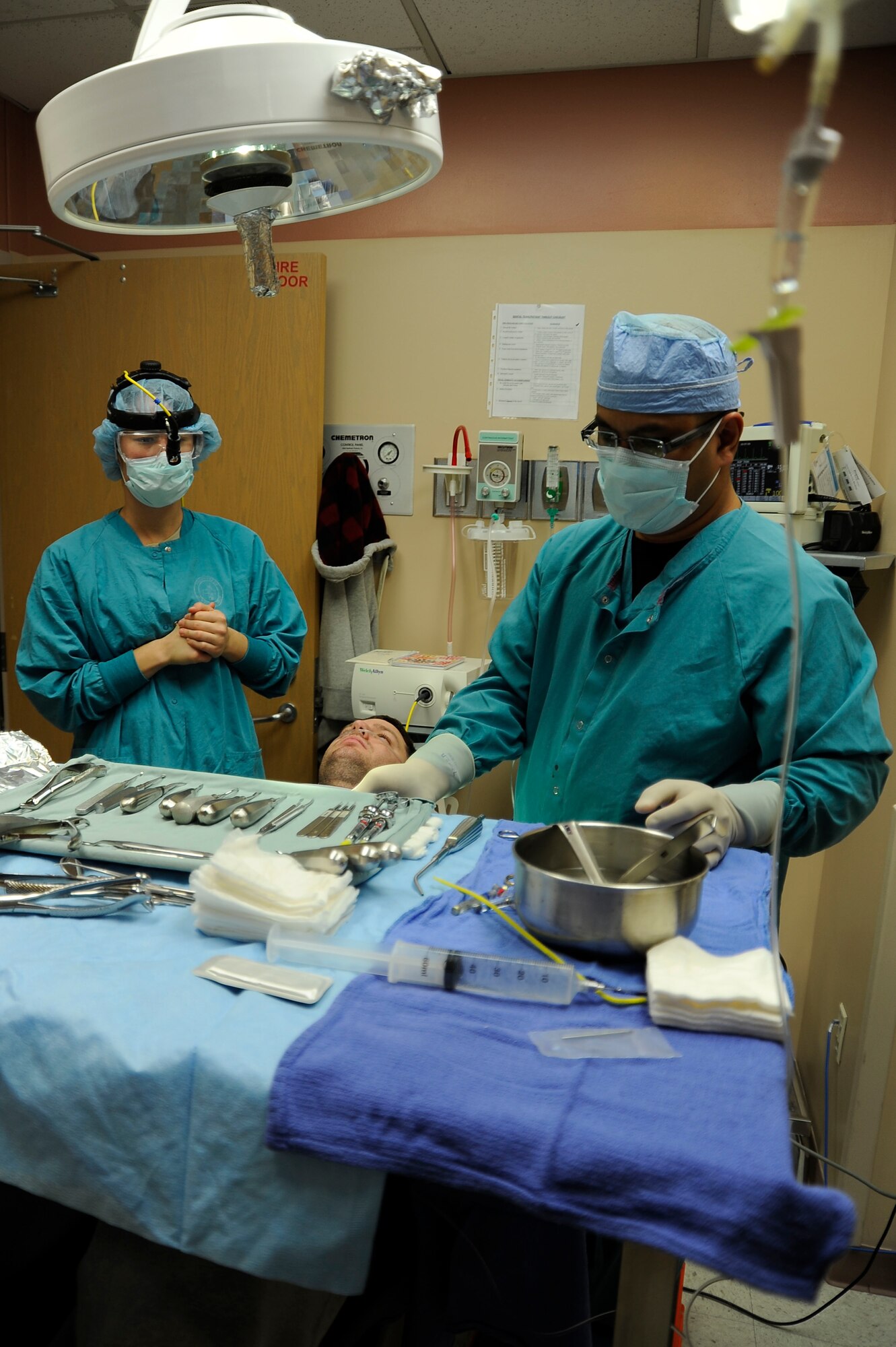 Capt. (Dr.) Heather Norton, 99th Dental Squadron Advanced Education in General Dentistry resident (left), and Raymond Estrella, 99th DS dental assistant (right), prepare a patient for surgery Dec. 2, 2013, at Nellis Air Force Base, Nev. Norton is undergoing a 12 month AEGD program to sharpen her dentistry skills beyond dental school. (U.S. Air Force photo by Airman 1st Class Timothy Young)