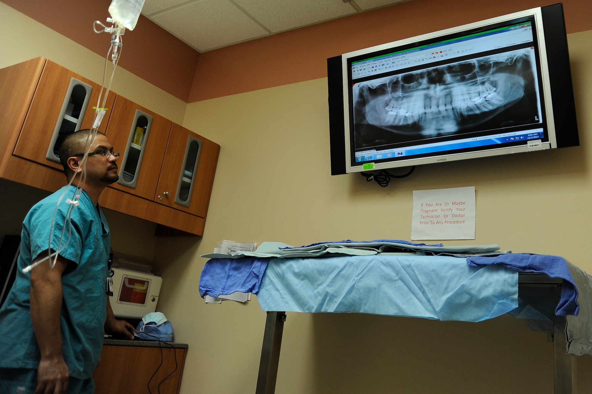 Raymond Estrella, 99th Dental Squadron dental assistant, examines an X-ray of a patient’s mouth Dec. 2, 2013, at Nellis Air Force Base, Nev. Dentists use X-rays to view the inside of teeth and roots in order to detect internal problems such as cavities. (U.S. Air Force photo by Airman 1st Class Timothy Young)