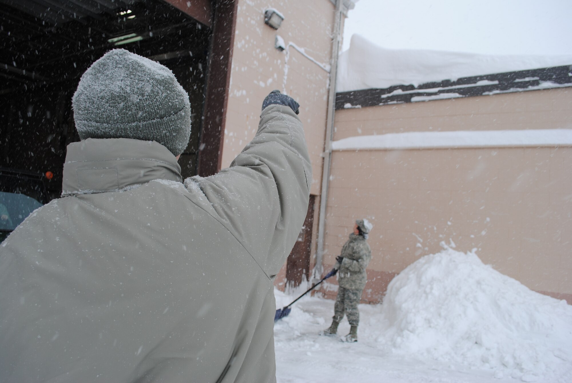 In true wingman fashion, Senior Airman Nicholas Richter, looks out for his fellow airfield systems technician, Staff Sgt. Michelle Carey, by pointing and making her aware of the heavy layer of snow on the roof of the 319th Communications Squadron headquarters building Dec. 4, 2013. Safety doesn't take a break for Airmen even on snow days. (U.S. Air Force photo/Staff Sgt. Luis Loza Gutierrez) 
