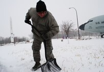 Senior Airman Michael Munguia, 319th Civil Engineer Squadron electrical power production technician, clears the entry way to a building on Grand Forks Air Force Base, N.D., Dec. 4, 2013. The 319th CES and other units on base equip government owned vehicles with shovels because of the threat heavy snow fall during winter. (U.S. Air Force photo/Staff Sgt. Luis Loza Gutierrez) 