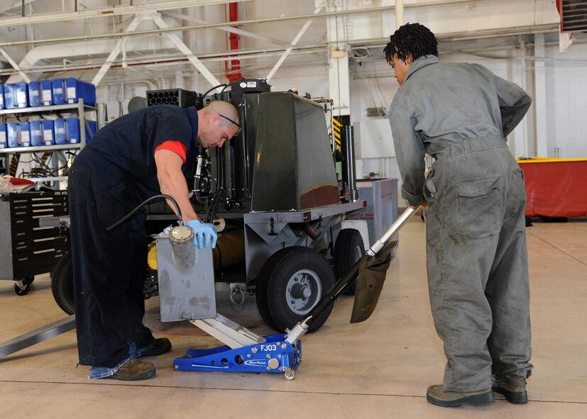 Tech. Sgt. Jacob Delloroso, left, 307th Aerospace Ground Equipment craftsman, and Airman 1st Class Toni Petty, 307th AGE journeyman, use a jack to lift a fuel tank on Barksdale Air Force Base, La., Dec. 3, 2013. Delloroso and Petty removed and replaced the fuel sending unit on a self-generating nitrogen cart. The fuel sending unit sends a signal to the fuel gauge showing the fuel levels for the SGNC. (U.S. Air Force photo/Senior Airman Joseph A. Pagán Jr.)