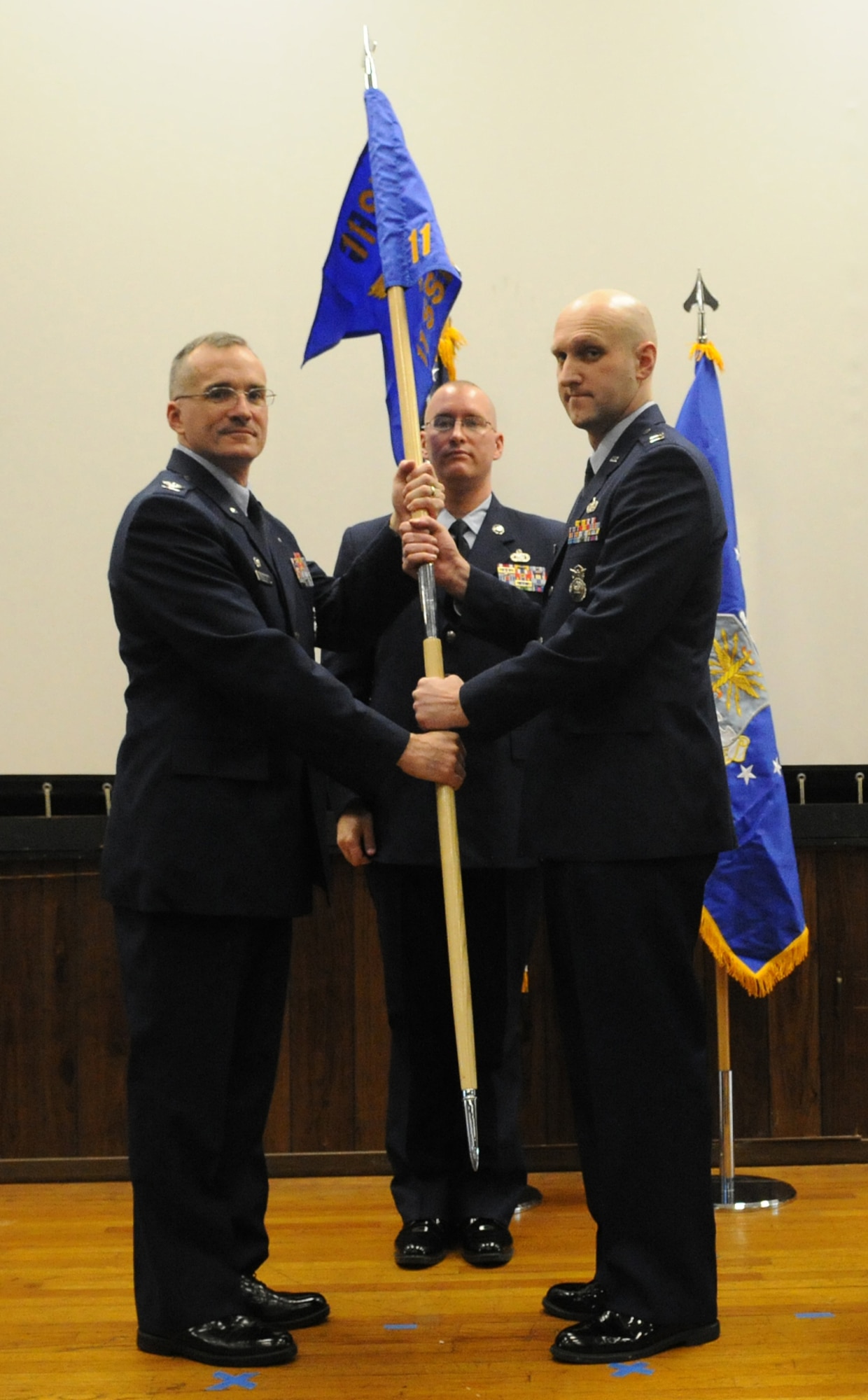 Capt. Charles Tenney (right), 11th Security Support Squadron commander, takes the guideon from Col. Erik Goepner, 11th Security Forces Squadron commander, at the activation ceremony of the 11th SSPTS, at Joint Base Andrews, Md., Dec. 3, 2013. The support squadron will provide an administrative role for the 11th Security Forces Group. (U.S. Air Force photo/Airman 1st Class Joshua R. M. Dewberry)