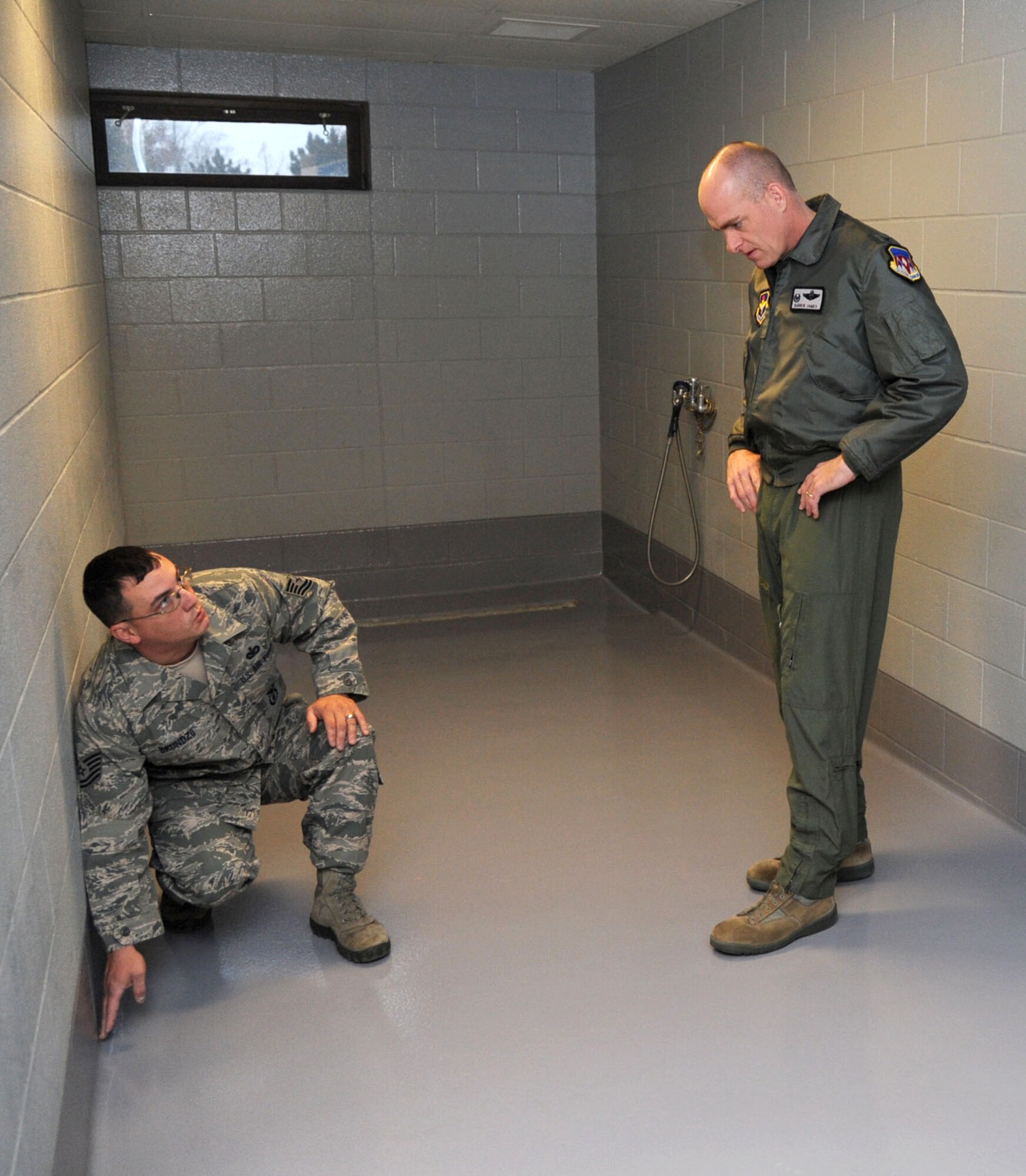 Tech. Sgt. Shawn Brundzo, kneeling, the 71st Security Forces Squadron kennel master, explains features of the new floors in the military working dog kennel to Col. Darren James, the 71st Flying Training Wing commander. (U.S. Air Force photo/ Senior Airman Frank Casciotta)