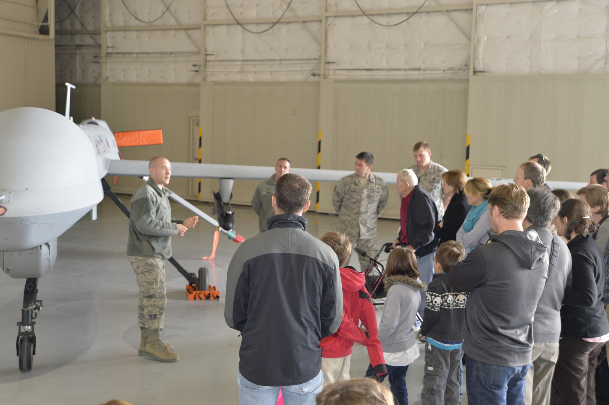 Retired U.S. Air Force colonel Linus Upson Jr. and his family receive a briefing about the MQ-1 Predator and MQ-9 Reaper aircraft during a tour Nov. 27, 2013. Upson, who was the base commander in 1945, brought his family to see the base he commanded. The base was once known as the Indian Springs Airport with the primary mission to train Airmen for combat. (U.S. Air Force photo by Senior Airman A.K.)