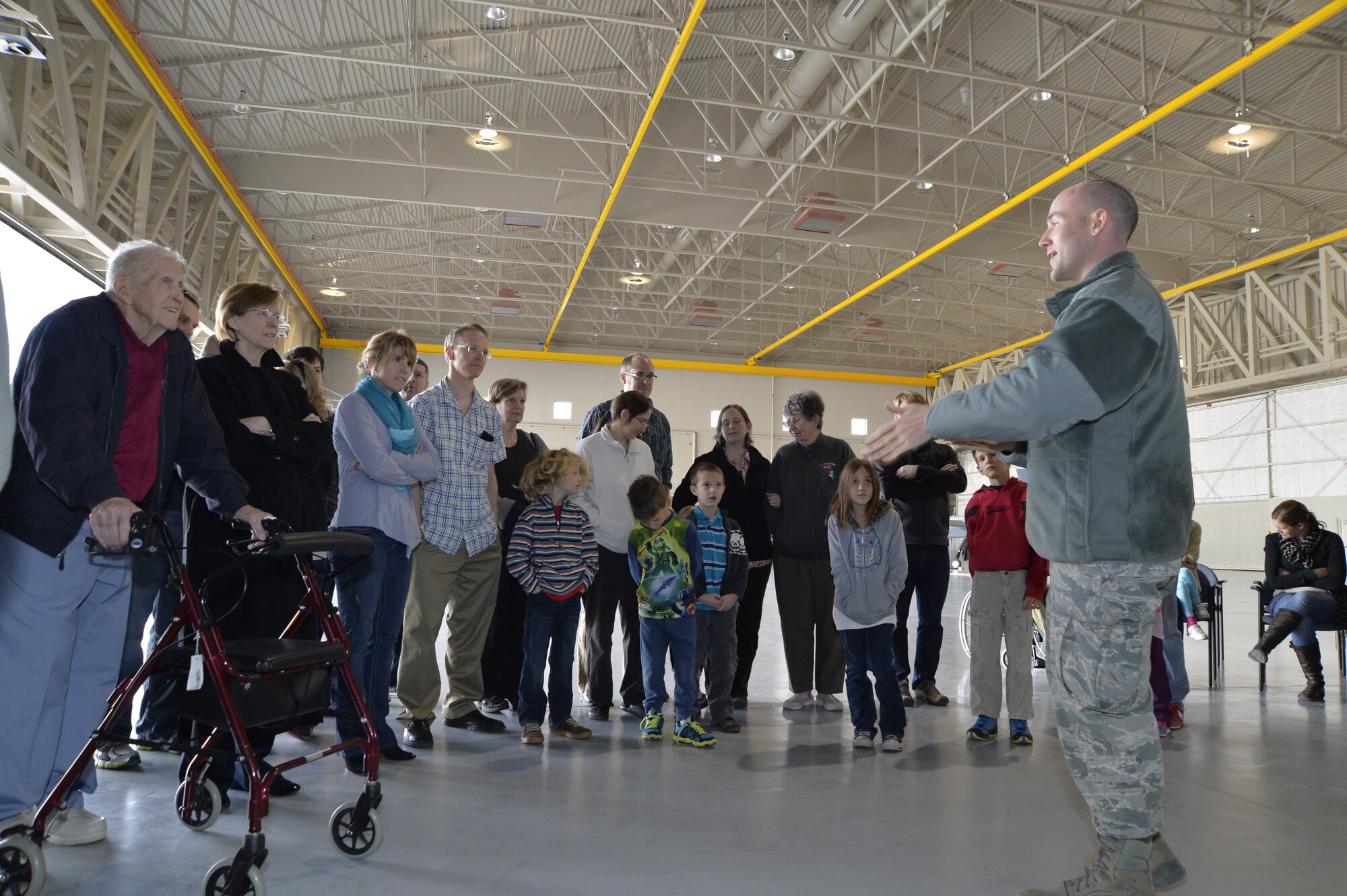 Retired U.S. Air Force colonel Linus Upson Jr. and his family receive a briefing about the MQ-1 Predator and MQ-9 Reaper aircraft during a tour Nov. 27, 2013. Upson (left), who was the base commander in 1945, brought his family to see the base he commanded. The base was once known as the Indian Springs Airport with the primary mission to train Airmen for combat. (U.S. Air Force photo by Senior Airman A.K.)