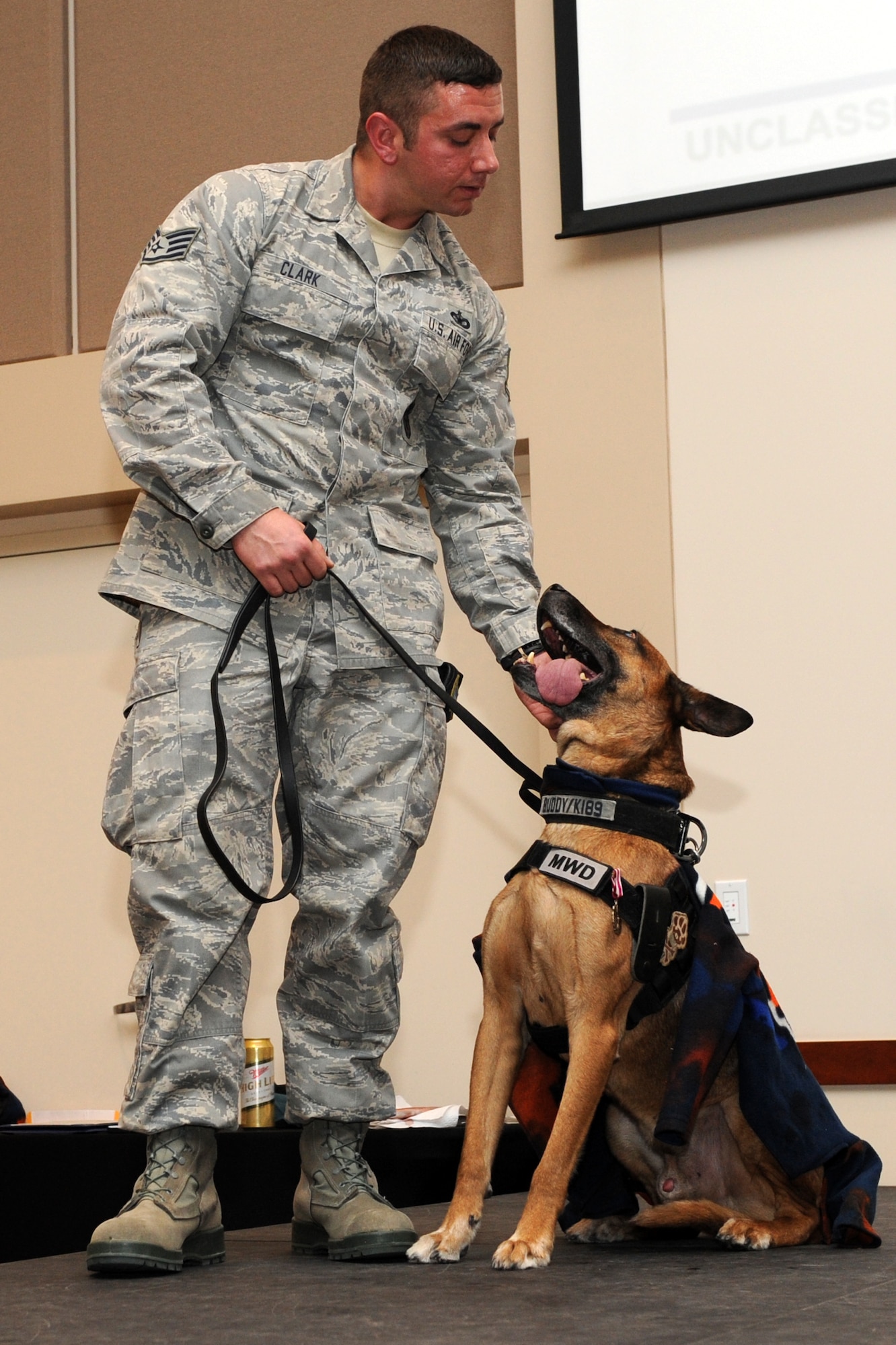 Staff Sgt. Michael Clark, 460th Security Forces Squadron military working dog handler, looks at Buddy, 460th SFS military working dog retired, at the conclusion of his retirement ceremony Nov. 18, 2013, at the Leadership Development Center on Buckley Air Force Base, Colo. Buddy retired after nearly nine years of service and five deployments. After the ceremony Buddy went home to live with his handler of three years. (U.S. Air Force photo by Senior Airman Marcy Copeland/Released)