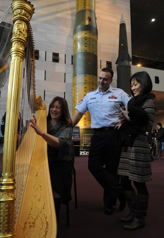Maria Banks plays Senior Master Sgt. Eric A. Sabatino’s harp at the Smithsonian's National Air and Space Museum in Washington, D.C., Dec. 3, 2013. Sabatino, a Concert Band and Orchestra Symphony solo harpist, allows Banks, a harpist and planetary geologist for the Earth and Planetary Studies at the Smithsonian Institution National Air and Space Museum, to play a song on his harp after the band’s flash mob performance. The band interacted with museum spectators after surprising them with a few holiday songs to spread word of their upcoming shows. (U.S. Air Force photo by/ Airman 1st Class Nesha Humes)