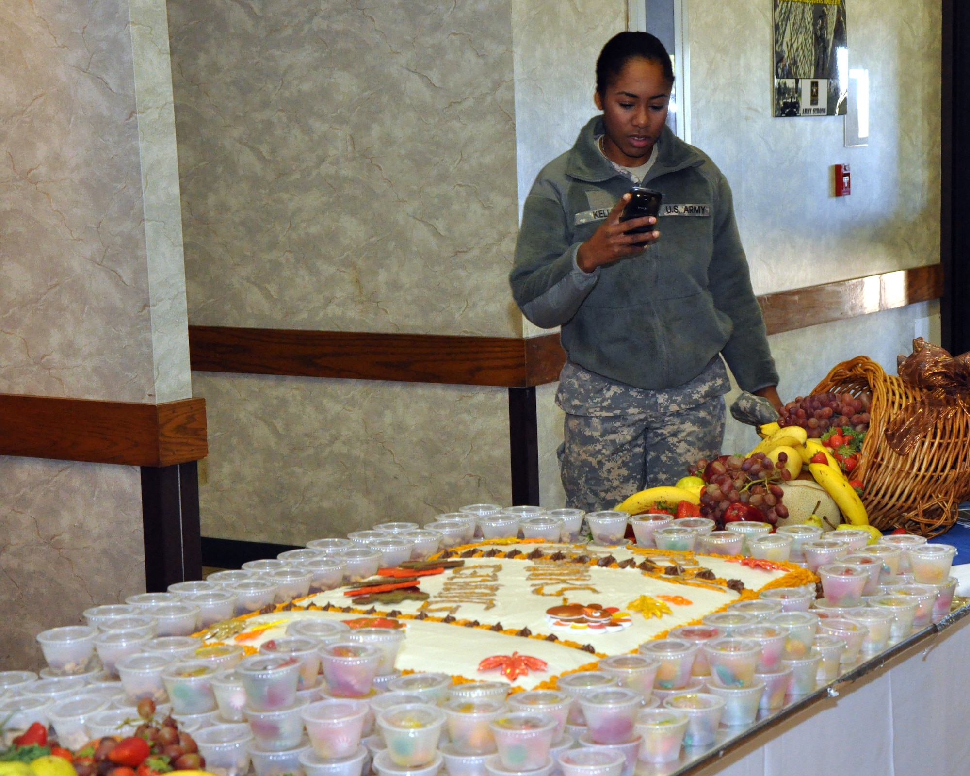 GOODFELLOW AIR FORCE BASE, Texas – Army Pvt. Sierra Kelly, Army 344th Military intelligence Battalion, photographs the Thanksgiving entrance display at the Western Winds Dining Facility Nov. 28. The display featured a cake, an ice sculpture, a decorative pine and two cornucopias. (U.S. Air Force photo/ Senior Airman Joshua Edwards)