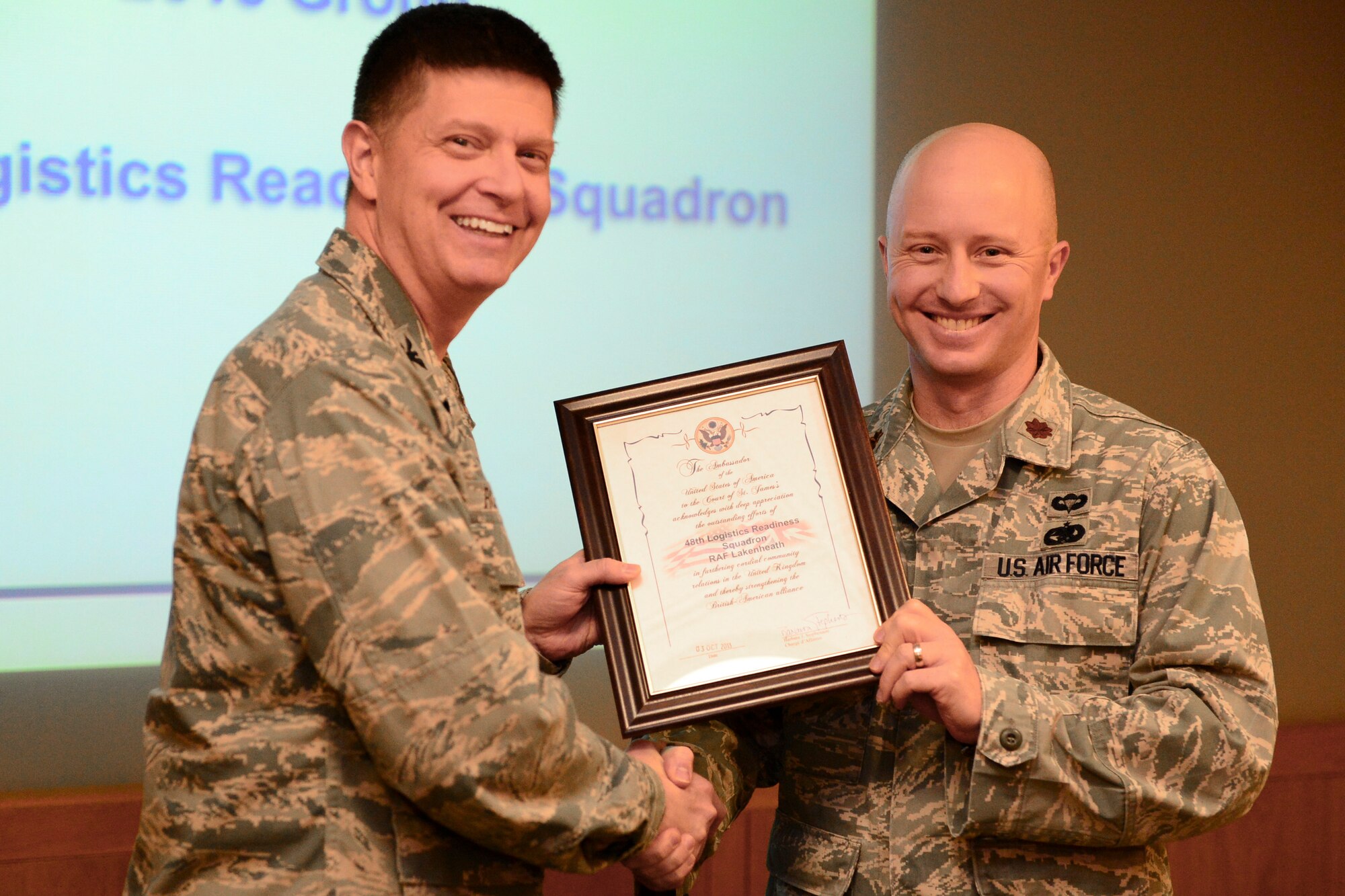 Col. Kyle Robinson, 48th Fighter Wing commander, presents Maj. Jarod Blecher, 48th Logistics Readiness Squadron commander, with a certificate of appreciation for outstanding efforts by the 48th LRS during the bi-monthly wing staff meeting at RAF Lakenheath, England, Dec. 2, 2013. Wing staff meetings are held to keep leadership abreast of local and national current events. (U.S. Air Force photo by Airman 1st Class Dawn M. Weber/Released)
