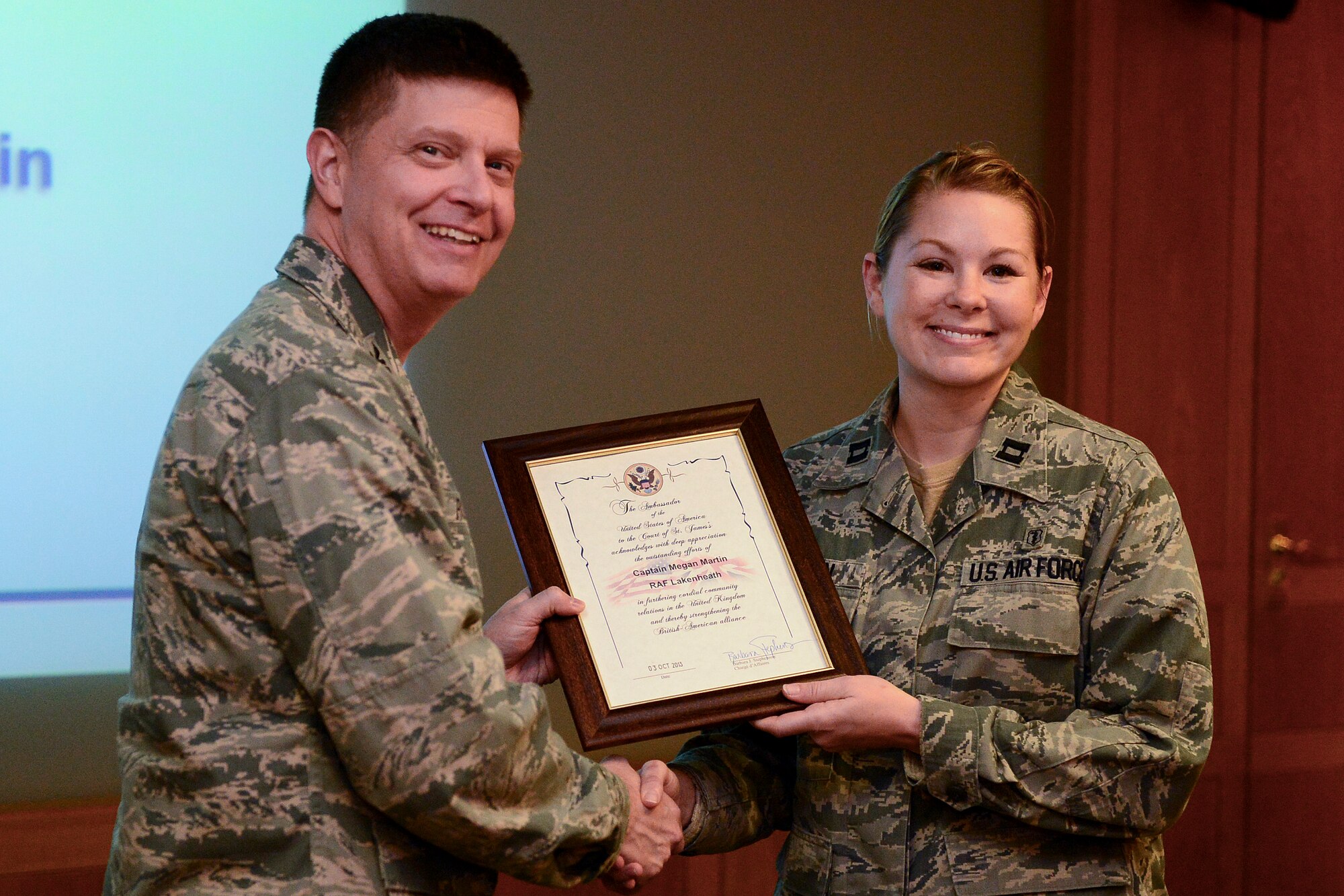 Col. Kyle Robinson, 48th Fighter Wing commander, presents Capt. Megan Martin, 48th Aerospace Medicine Squadron chief of public health operations, with a certificate of appreciation during the bi-monthly wing staff meeting at Royal Air Force Lakenheath, England, Dec. 2, 2013. Wing staff meetings are held to keep leadership abreast of local and national current events. (U.S. Air Force photo by Airman 1st Class Dawn M. Weber/Released)