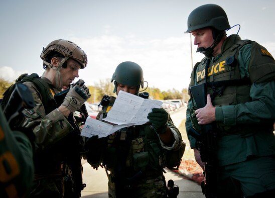 Patrol Officer Lucas Kraus and Cpl. Pierre Batiste (left and middle), members of the Crestview Police Department SWAT team, check the map of the Naval School Explosive Ordnance Disposal building during an active shooter exercise on Eglin Air Force Base, Fla., Dec. 3. Police and first responders from Eglin and the surrounding communities participated in the joint exercise in which a person with two weapons entered the building and began shooting students.  The SWAT team made sure the building was safe to enter.  Then firefighters moved the victims out to the triage area where local emergency medical technicians provided care.  (U.S. Air Force photo/Samuel King Jr.)