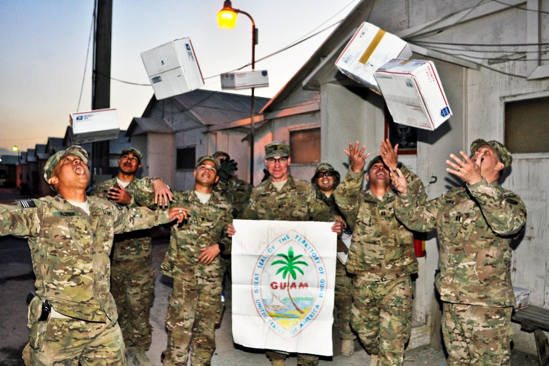 U.S. soldiers toss their care packages into the air on Camp Phoenix in Kabul, Afghanistan, Nov. 21, 2013. Project Minagof, a program led by Guam's executive leaders, provided the packages to about 600 soldiers assigned to Headquarters Company, 1st Battalion, 294th Infantry Regiment, Guam Army National Guard.