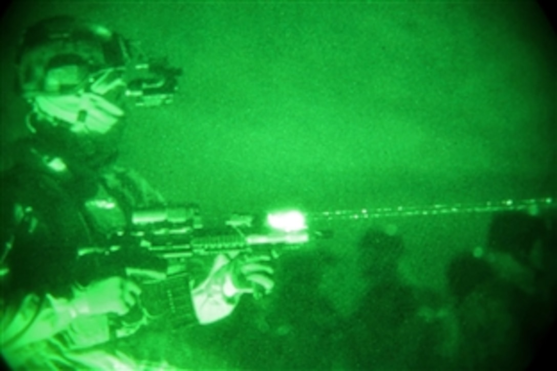 As seen through a night-vision device, an Afghan commando identifies the first compound that commandos and U.S. coalition forces are going to clear during a night operation in the Sairobi district of Afghanistan's Kabul province, Dec. 2, 2013. 