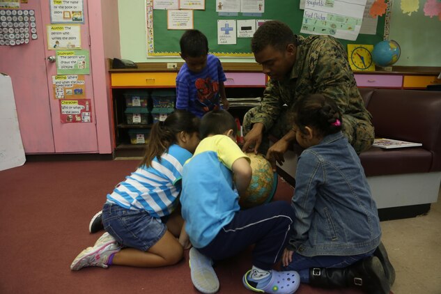 Lance Cpl. Sterling L. Meriweather helps children at Tinian Elementary School find Tinian on a globe during a community relations event Dec. 4. The servicemembers are here participating in Exercise Forager Fury II. FF II is an aviation training relocation event intended to meet U.S.-Japan bilateral goals such as reduced local impacts by dispersing the training to other areas and increased operational readiness.  The service members volunteered time to spend time with the children. Meriweather is a satellite communications specialist with Marine Air Control Group 18, 1st Marine Aircraft Wing, III Marine Expeditionary Force.

