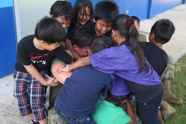 Lance Cpl. Michael Bridenstine plays with a group of children at Tinian Elementary School during a community relations event Dec. 4. Bridenstine is here as part of Exercise Forager Fury II. The purpose of exercise FF II is to employ and assess combat power generation and operations in a deployed, austere and unimproved environment.  The service members volunteered time to to play games and spend time with the children. Bridenstine is a chemical biological radiological nuclear defense specialist with Marine Wing Support Squadron 171, Marine Aircraft Group 12, 1st Marine Aircraft Wing, III Marine Expeditionary Force.
