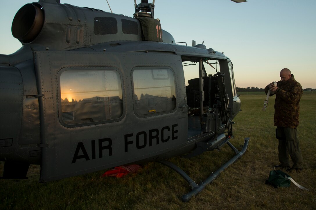 Royal New Zealand Air Force Sgt. Cameron Geoff, a helicopter crewman with Royal New Zealand Air Force Squadron 3, rolls cargo straps after an evening flight mission as part of exercise Southern Katipo 2013 (SK13) at Timaru Airfield, Timaru, New Zealand, Nov. 19, 2013. SK13 is a New Zealand led training exercise that strengthens military relations between coalition forces and helps the New Zealand Defence Force further develop its amphibious capabilities. (U.S. Marine Corps photo by Cpl. Luis A. Vega/ Released)