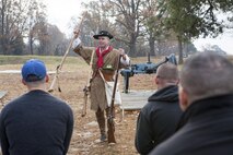 Yorktown, Va. (Dec. 3, 2013) - Maj. David McCombs, a staff ride action officer, Headquarters and Service Battalion, U.S. Marine Corps Forces Command, shows and explains the gear sharpshooters and infantrymen would have used at the siege of Yorktown to the Marines and Sailors of MARFORCOM. Because McCombs is a Revolutionary War reenactor, he was able to dress up as a sharpshooter and show the Marines what they would have looked like, and why.