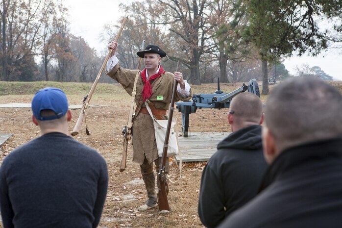Yorktown, Va. (Dec. 3, 2013) - Maj. David McCombs, a staff ride action officer, Headquarters and Service Battalion, U.S. Marine Corps Forces Command, shows and explains the gear sharpshooters and infantrymen would have used at the siege of Yorktown to the Marines and Sailors of MARFORCOM. Because McCombs is a Revolutionary War reenactor, he was able to dress up as a sharpshooter and show the Marines what they would have looked like, and why.