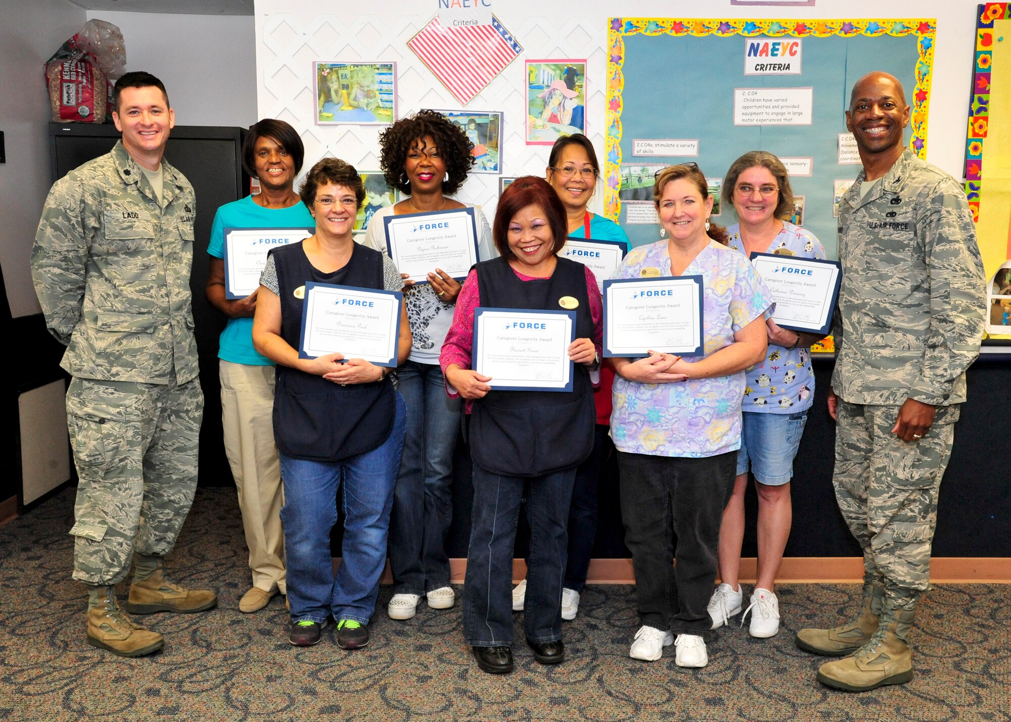 Lt. Col. Todd Ladd, left, 56th Force Support Squadron commander, and Col. Nathan Mooney, 56th Mission Support Group commander, pose with child caregivers Nov. 18 at the Luke Air Force Base Child Development Center. The women were awarded for more than 20 years of dedicated service to the CDC. (U.S. Air Force photo/Senior Airman Grace Lee)