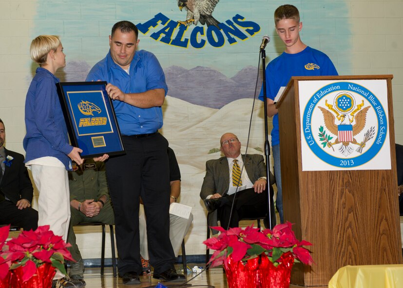 Students of Holloman Middle School present the teaching staff of HMS with a framed “Holloman Falcons” t-shirt to commemorate the schools achievement of the National Blue Ribbon at Holloman Air Force Base N.M., Dec. 3. The National Blue Ribbon is a Department of Education award given to schools that show great improvement or academic excellence by its students. (U.S. Air Force photo by Airman 1st Class Chase Cannon/Released)