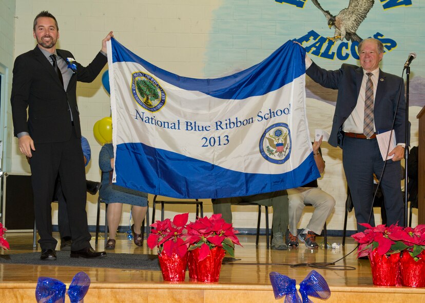 Jeff Gephart, a Holloman Middle School teacher, and George Straface, Alamogordo Public Schools superintendent, present the flag naming HMS as a 2013 National Blue Ribbon award winner at Holloman Air Force Base N.M., Dec. 3. The National Blue Ribbon is a Department of Education award given to schools that show great improvement or academic excellence by its students. (U.S. Air Force photo by Airman 1st Class Chase Cannon/Released)