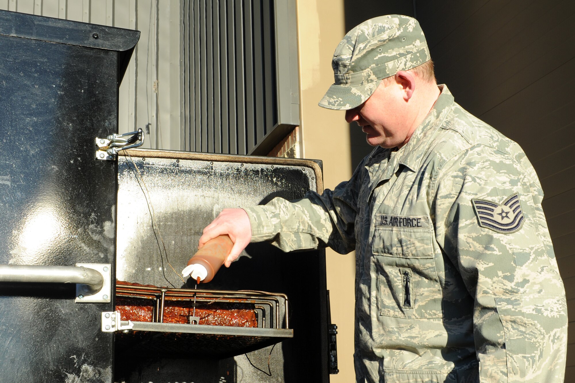 Tech. Sgt. Sheldon Mason, 341st Maintenance Operations Squadron mechanical pneudraulics section assistance NCO in charge, pours barbecue sauce on ribs behind Bldg. 1439 on Nov. 26 during an office lunch. Mason specializes in barbecue and caters to various events on Malmstrom Air Force Base including retirement ceremonies, squadron functions and promotion ceremonies. (U.S. Air Force photo/Senior Airman Katrina Heikkinen)