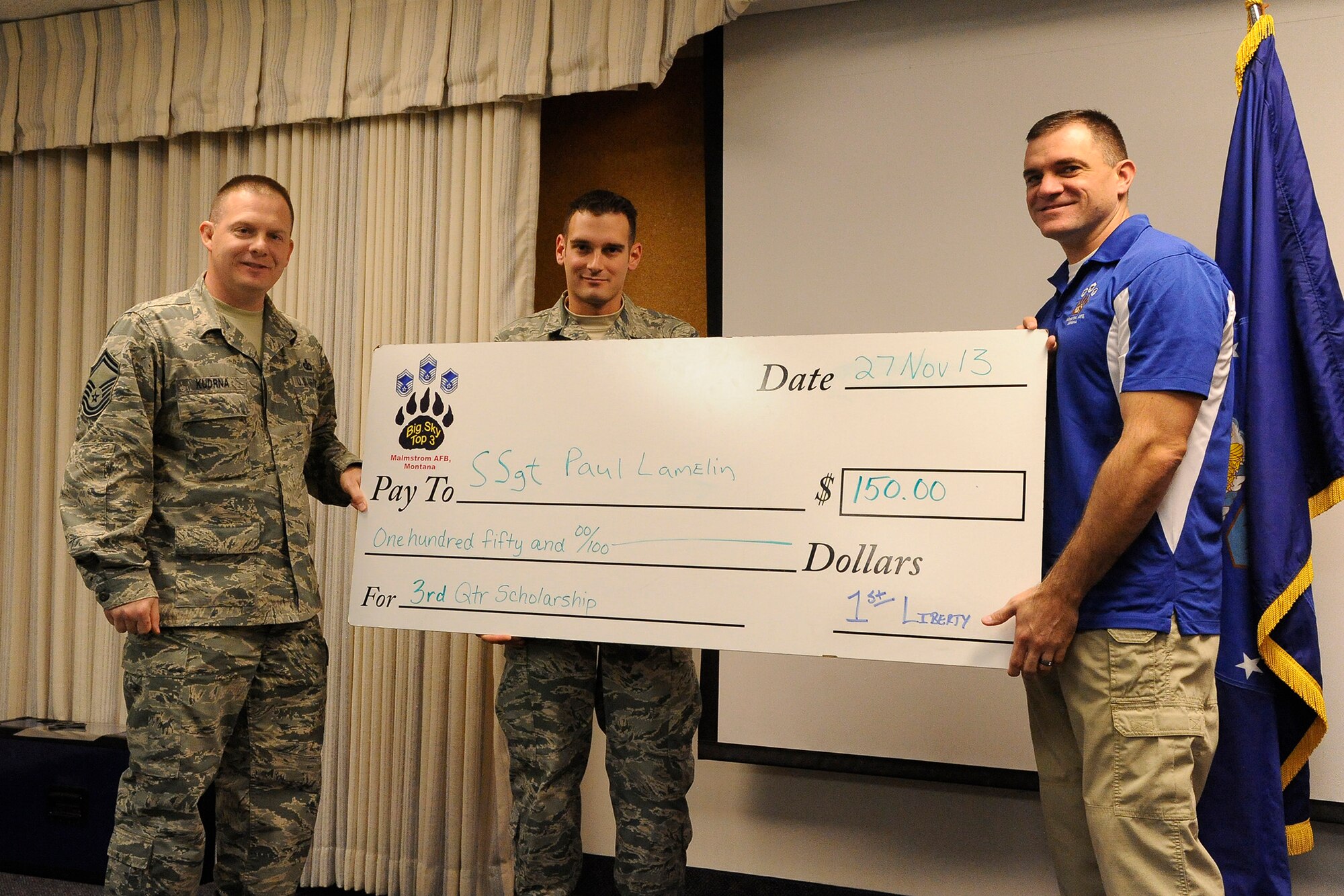 Staff Sgt. Paul Lamelin, 341st Security Forces Group member, receives a check from Senior Master Sgts. William Kudrna, 341st Comptroller Squadron superintendent (left), and Paul Stansbury, 341st Security Forces Group Tactical Response Force Operations superintendent, at the SFG auditorium Nov. 27. Lamelin received the award from the Big Sky Top 3 Association for his essay regarding the fairness of Air Force physical fitness tests. (U.S. Air Force photo/Airman 1st Class Collin Schmidt)