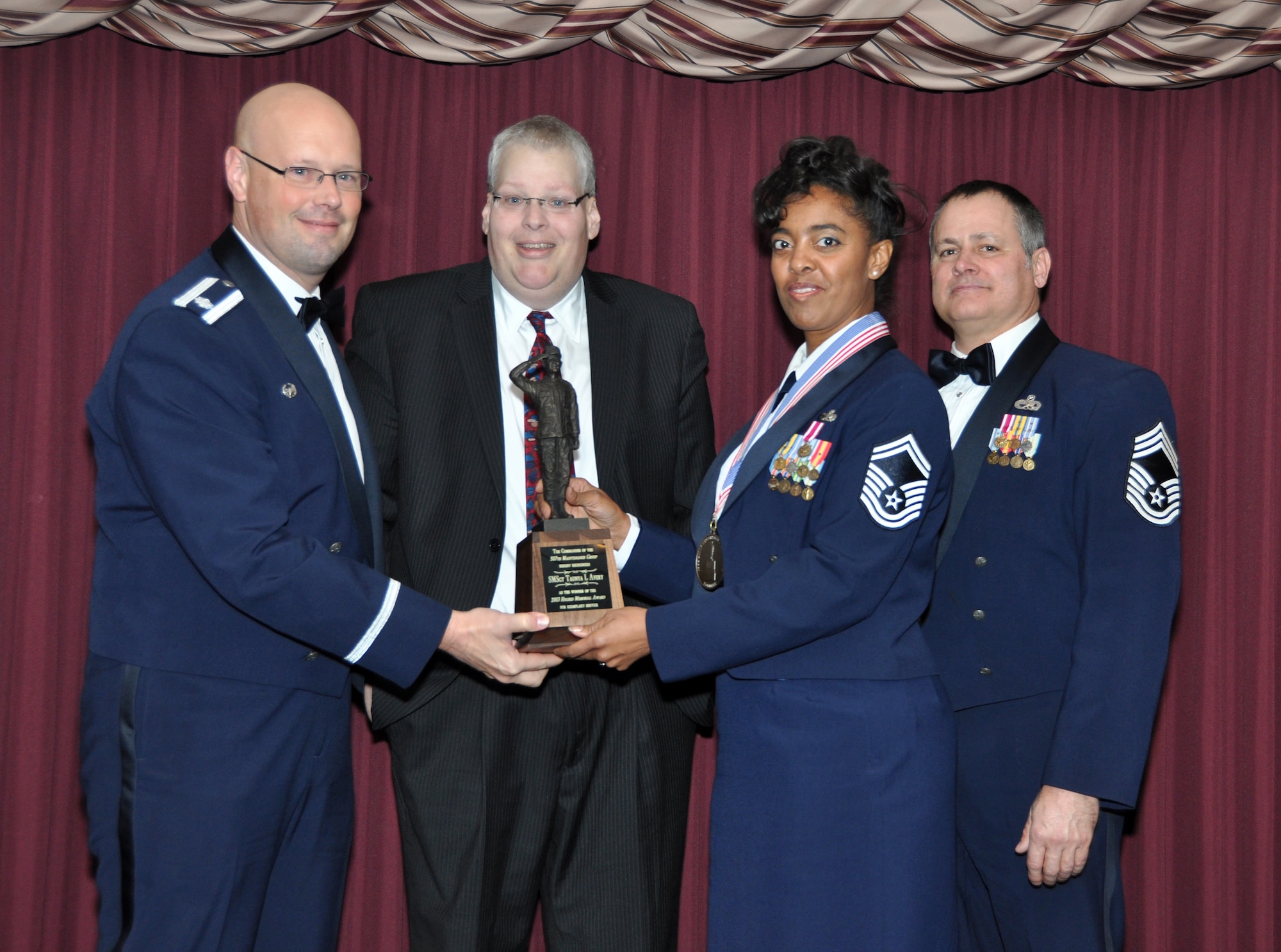 Senior Master Sgt. Taunya Avery receives the Gary Hughes Award from 507th Maintenance Group Commander, Lt. Col. Travis Caughlin, far left, Gary Hughes, left and Maintenance Squadron Superintendent Chief Master Sgt. Ronald Mitchell during the annual awards banquet at the Tinker club Nov. 23, 2013.  (U.S. Air Force photo/Maj. Jon Quinlan)