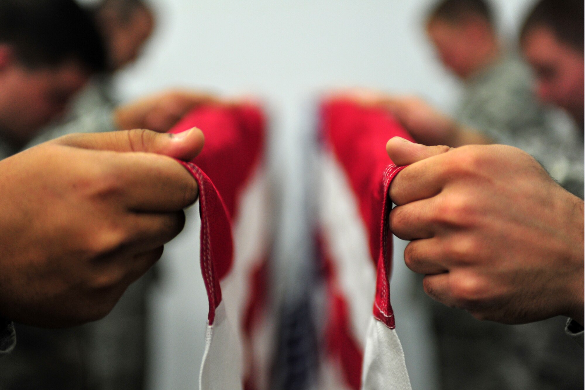 Members of the base honor guard practice folding a flag at Fairchild Air Force Base, Wash., Nov. 25, 2013. Prior to a ceremony, Airmen practice their technique multiple times to ensure they are prepared for the live ceremony. (U.S. Air Force photo by Senior Airman Taylor Curry/Released))