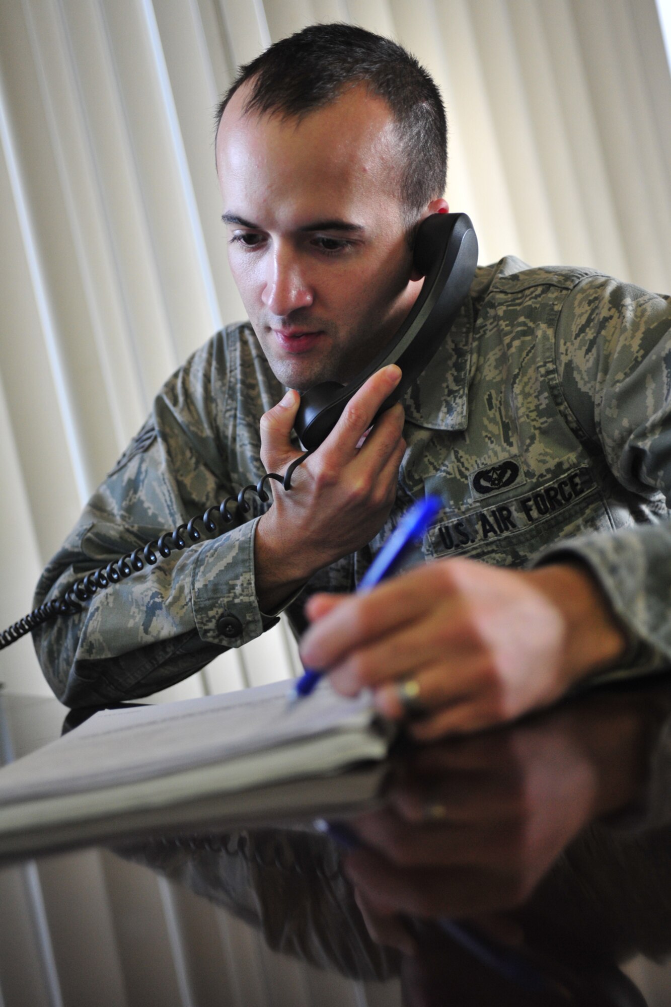 Senior Airman Travis Barfield, ceremonial guardsman, answers the phone to receive a ceremony request at Fairchild Air Force Base, Wash., Nov. 25, 2013. When taking requests, it is important to record as much information as possible for a ceremony to ensure mission success. (U.S. Air Force photo by Senior Airman Taylor Curry/Released)