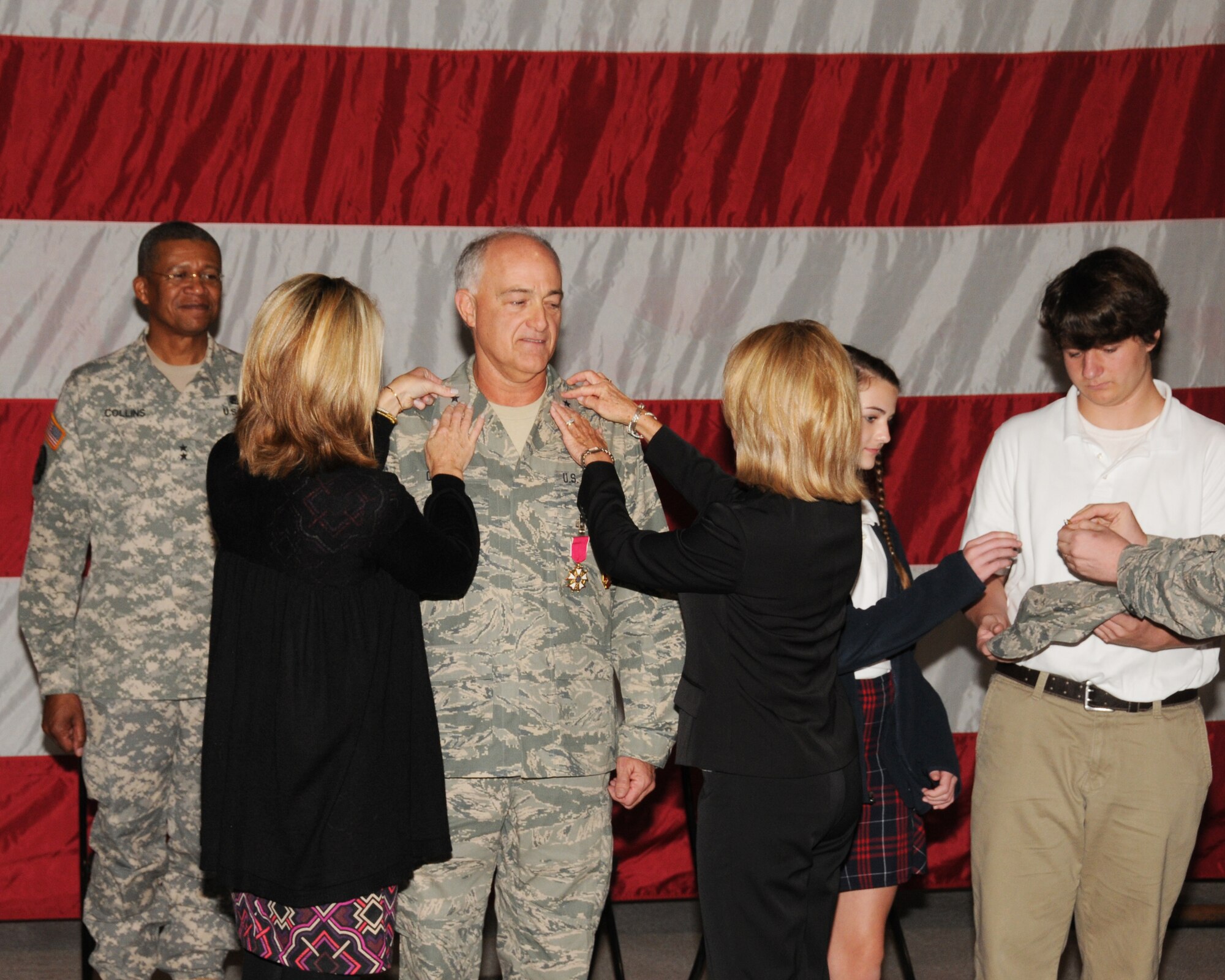 Major General Augustus L. Collins, Adjutant General of the Mississippi National Guard, looks on as 186th Air Refueling Wing Commander Colonel Franklin Chalk's family pins him with the rank of brigadier general during his retirement ceremony at Key Field Air National Guard Base, Mississippi November 22, 2013.The family members pictured are his daughter Stacey (left), wife Sharon, and grandkids Adeline and Jackson.  (U.S. Air National Guard photo by Senior Master Sgt. Richard Davis/Released)