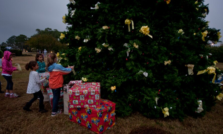 Children place yellow bows on the tree during the holiday tree lighting ceremony at the Air Park on Hurlburt Field, Fla., Dec. 4, 2013. The yellow bows represent deployed Airmen. (U.S. Air Force photo/Senior Airman Krystal M. Garrett)