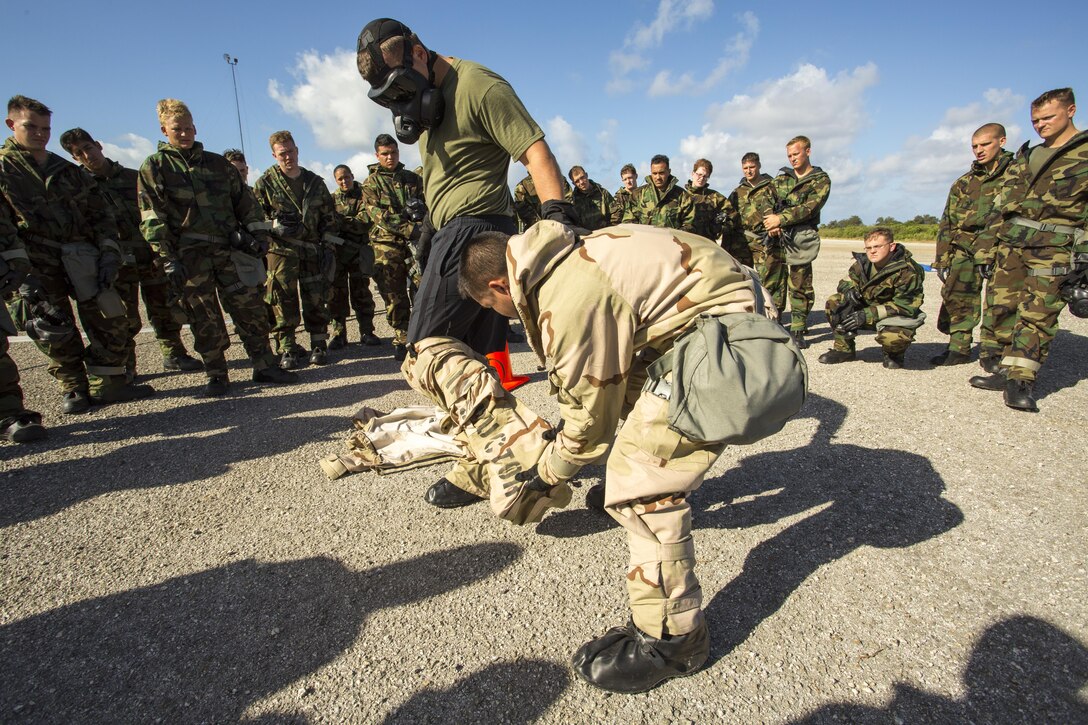 Staff Sgt. Brian Smith, center left, and Cpl. Matthew Ahn demonstrates a proper mission orientated protective posture gear exchange Dec. 3 at Tinian’s North Field during exercise Forager Fury II. The series of exercises, which Marine Aircraft Group 12 is conducting in the Mariana Islands, focus on refining core skills within the squadrons and MAG. This, in turn prepares them to function as an integrated air unit able to perform a wide range of missions. Chemical Biological Radiological Nuclear Defense Marines conducted annual unit-level training to exercise specific unit capabilities and cross train other Marines from sections. Smith is the CBRN chief and Ahn is the noncommissioned officer in charge of CBRN with MAG- 12, 1st Marine Aircraft Wing, III Marine Expeditionary Force. 