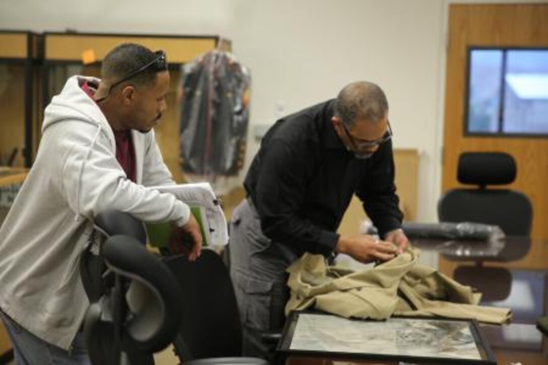 Rob L. Jackson (right), public affairs officer on Marine Corps Logistics Base Barstow, Calif., shows base personnel Marine Corps uniform items from the Korean and Vietnam War era, Nov. 21., at MCLB Barstow’s Historical Gallery. The gallery is a work in progress, tentatively slated to open Feb. 5