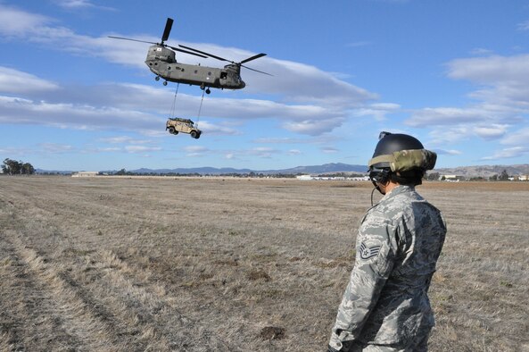 Staff Sgt. Ryan Torralba watches a CH-47 Chinook as it carries a Humvee with a cargo sling Nov. 21, 2013, on Travis Air Force Base. Calif. Torralba is assigned 60th Aerial Port Squadron aerial porter. (U.S. Air Force photo/Staff Sgt. Patrick Harrower)