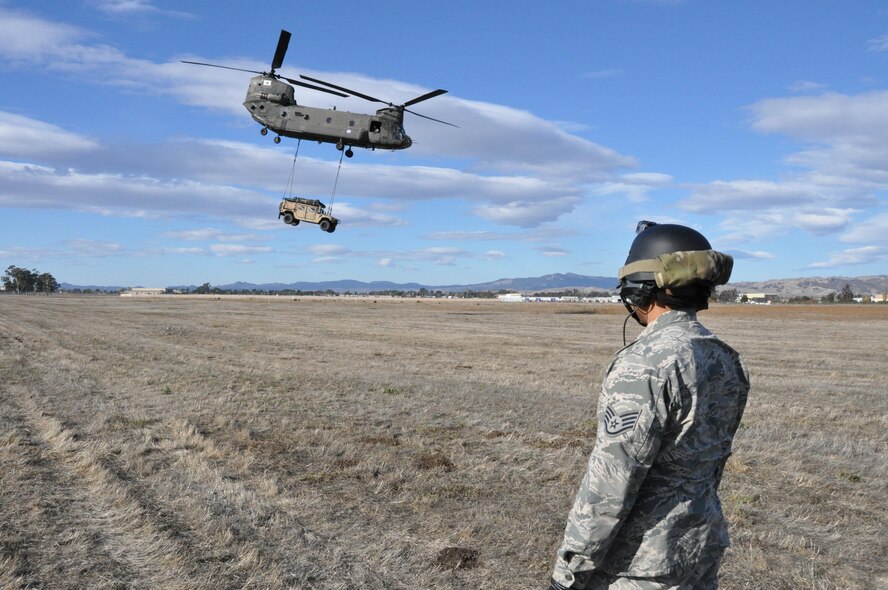 Staff Sgt. Ryan Torralba watches a CH-47 Chinook as it carries a Humvee with a cargo sling Nov. 21, 2013, on Travis Air Force Base. Calif. Torralba is assigned 60th Aerial Port Squadron aerial porter. (U.S. Air Force photo/Staff Sgt. Patrick Harrower)