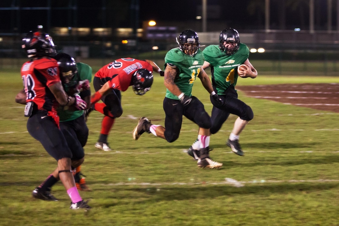 Brandon Erickson, the quarterback for the 3rd Marine Regiment Wolf Pack runs around the Marine Aircraft Group 24 Bandits’ defense, Dec. 4, 2013, at Riseley Field. The Wolf Pack will face the 1st Battalion, 12th Marine Regiment Savages for the championship title.(U.S. Marine Corps photo by Cpl. Nathan Knapke) 