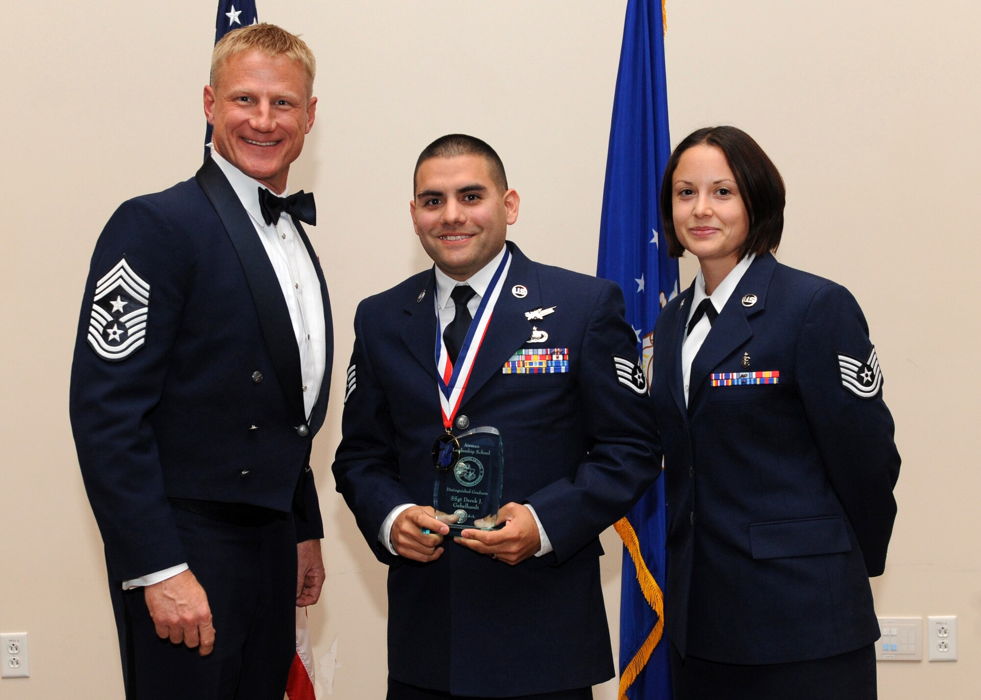 Staff Sgt. Derek J. Gebelhardt, 566th Intelligence Squadron, center, receives the Distinguished Graduate Award during the Buckley Airman Leadership School Class 14-A graduation Dec. 4, 2013, at the Leadership Development Center on Buckley Air Force Base, Colo. The Distinguished Graduate Award is presented to the person with the second highest overall average in all graded areas who demonstrated a high level of leadership skills during ALS. (U.S. Air Force photo by Senior Airman Marcy Copeland/Released)