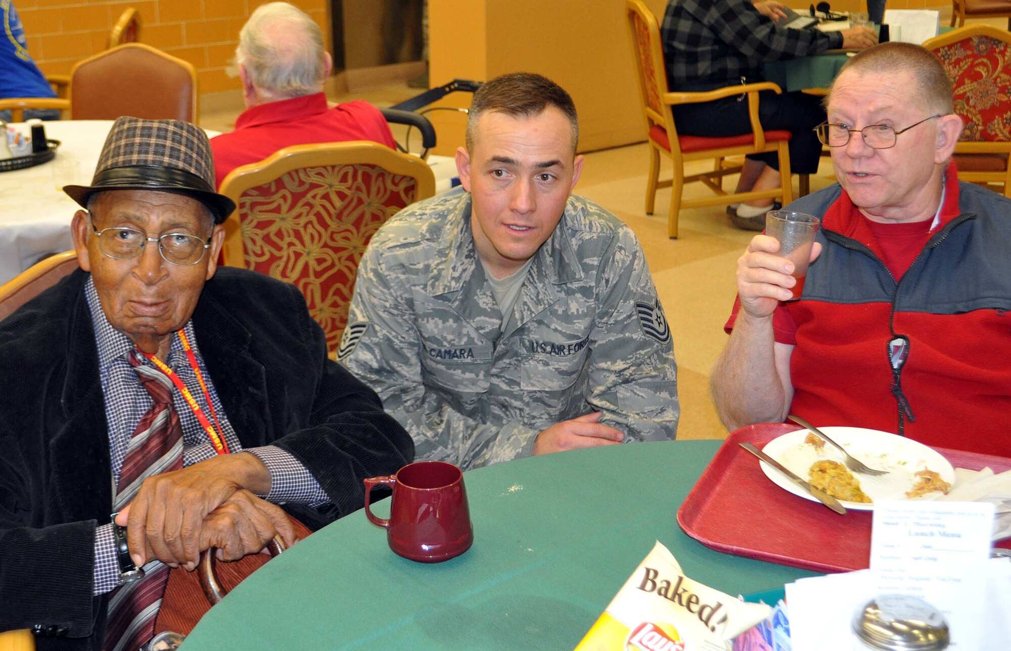 TRAVIS AIR FORCE BASE, Calif. -- Technical Sgt. Antonio Da Camara, 349th Force Support Squadron, visits with two veterans at the Yountville Veterans Home on Thanksgiving Day. Da Camara brought along his wife and daughter to share in the joy of serving the holiday meal, and the chance to visit with those who paved the way for today's military. Sharing Thanksgiving with our veterans has been a tradition for a number of years, for Travis Airmen. (U.S. Air Force photo/SMSgt. (ret) Ellen Hatfield)
