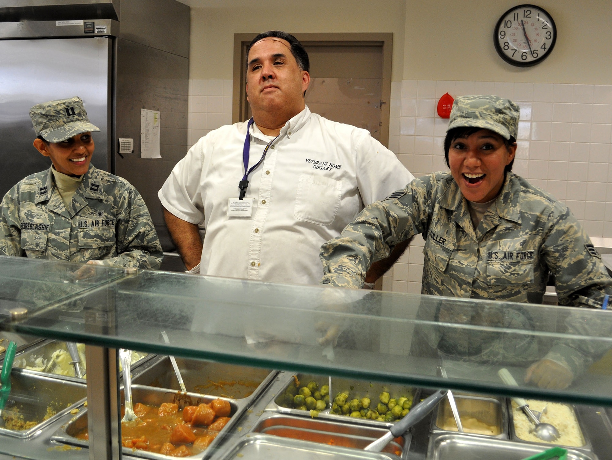 TRAVIS AIR FORCE BASE, Calif. -- Capt. Selamawit Gebreslassie and Senior Amn. Luz Fuller help the king of the Yountville kitchen crew serve up the Thanksgiving meal, at the Yountville Veterans Home. They joined about 130 Travis Airmen, to serve and visit with the veterans at the Home, who look forward to this yearly visit from those still in uniform. Gebreslassie is with the 349th Medical Squadron, and Fuller is with 349th Logistics Readiness Squadron. (U.S. Air Force photo/SMSgt. (ret) Ellen Hatfield)
