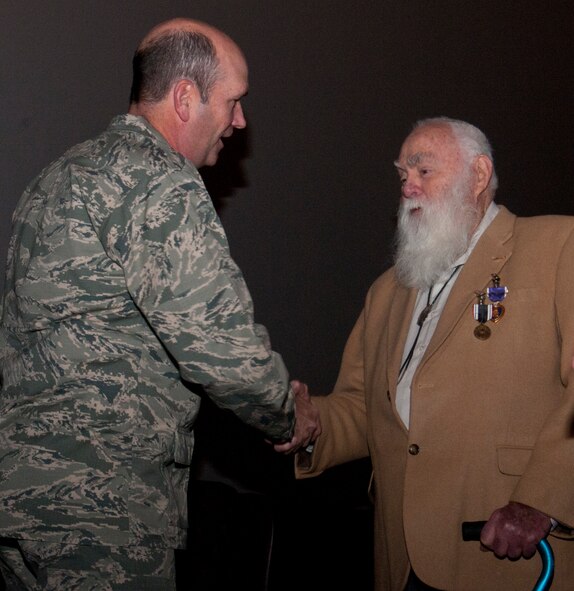 Col. Trevor Flint, 90th Maintenance Group commander, shakes hands with 1st Lt. (Ret.) Paul Kniss after a medal presentation ceremony. Kniss was presented the Purple Heart medal and Prisoner of War medal he wears on his lapel in the F.E. Warren Air Force Base, Wyo., Theater Dec. 5, 2013. After the ceremony, droves of attendees lined up for the opportunity to congratulate, thank and shake hands with Kniss. Approximately 400 people attended the ceremony (U.S. Air Force photo by Airman 1st Class Jason Wiese)