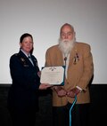 Col. Tracey Hayes, 90th Missile Wing commander, and 1st Lt. (Ret.) Paul Kniss pose in the F.E. Warren Air Force Ba¬se, Wyo., Theater Dec. 5, 2013, with a certificate of recognition stating he is a recipient of the Purple Heart medal. (U.S. Air Force photo by Airman 1st Class Jason Wiese)