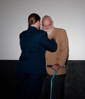 Col. Tracey Hayes, 90th Missile Wing commander, pins a Prisoner of War medal on 1st Lt. (Ret.) Paul Kniss during a ceremony in the F.E. Warren Air Force Base, Wyo., Theater Dec. 5, 2013, for time he spent captive in North Korea during the Korean Conflict. (U.S. Air Force photo by Airman 1st Class Jason Wiese)