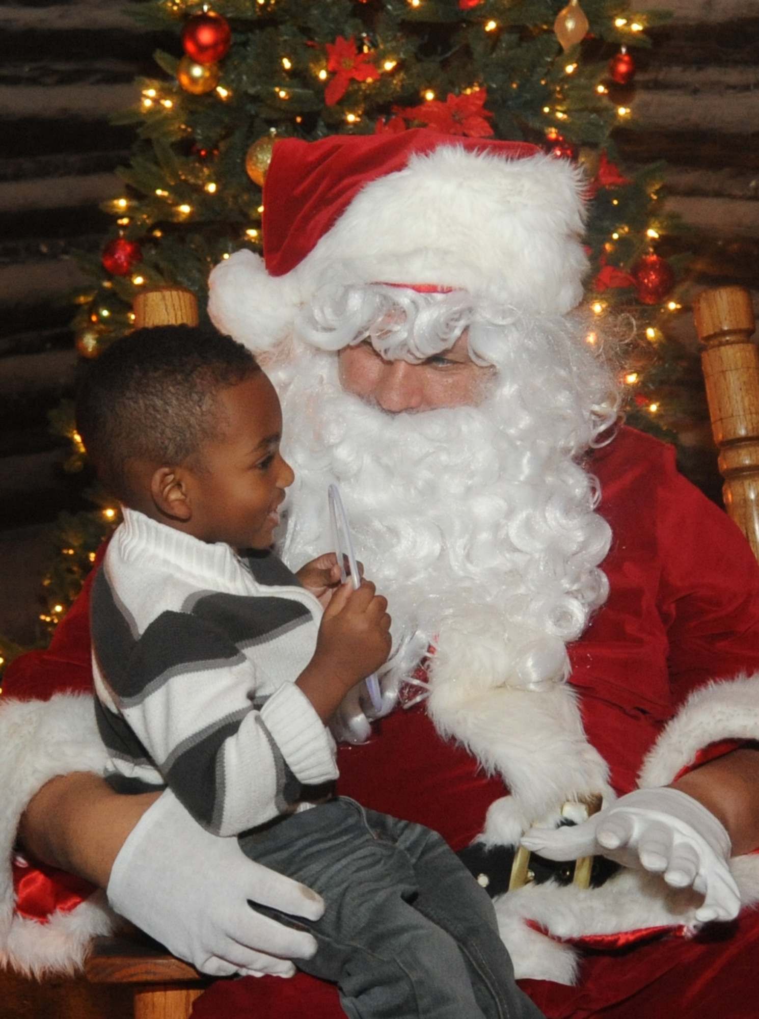 Santa Claus visits with the son of Staff Sgt. Blair Rashaud Sr., 81st Security Forces Squadron, during Keesler’s annual Christmas in the Park celebration Dec. 4, 2013, at marina park, Keesler Air Force Base, Miss. The event, hosted by Outdoor Recreation, included a tree lighting ceremony, tour train rides, holiday music, cookie decorating and free food and beverages. (U.S. Air Force photo by Kemberly Groue)
