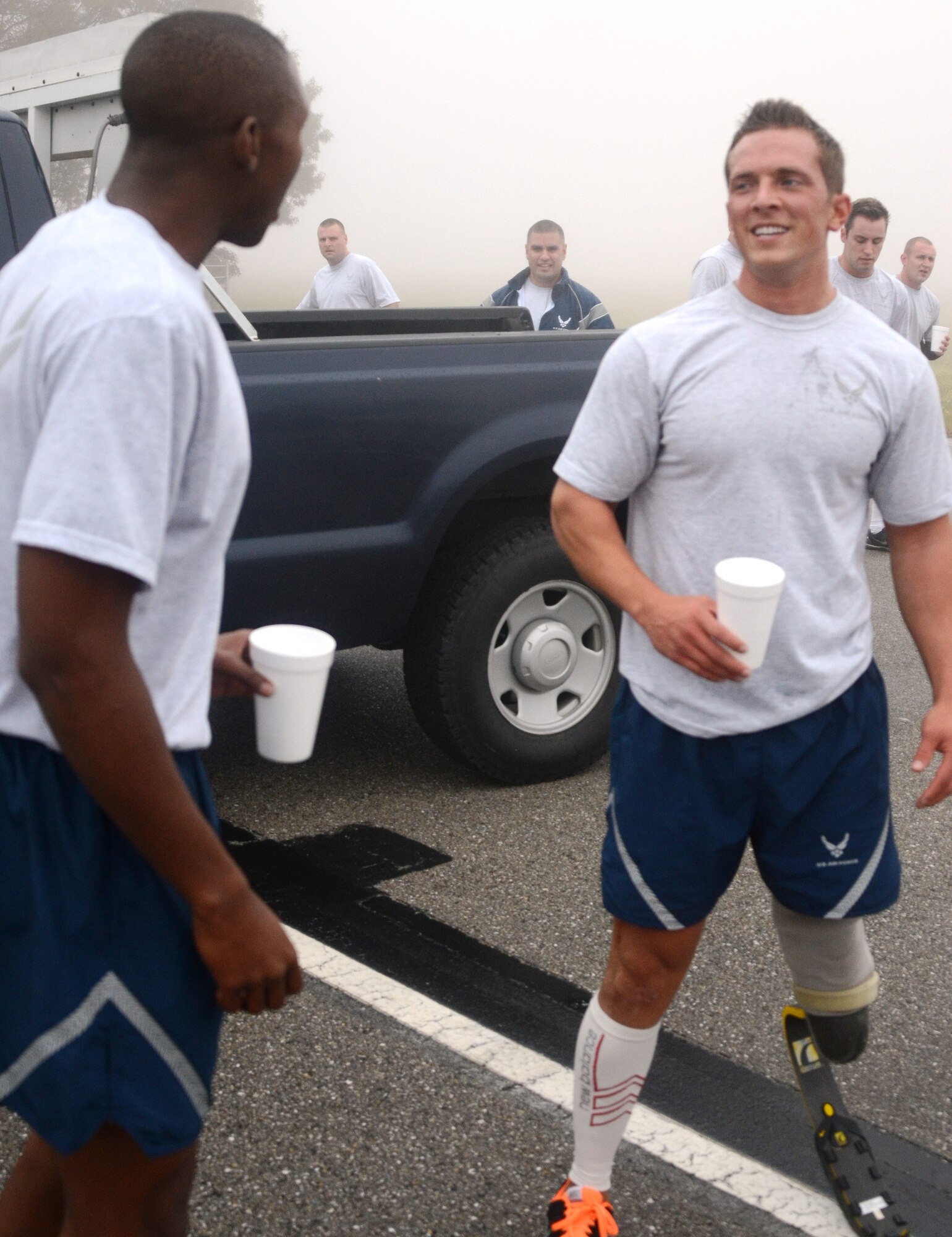 After a fast time in the 1.5 mile run, Senior Airman Gideon Connelly, right, relaxes with a drink with SrA Daniel Gernerette, the first place finisher in 175th Maintenance Squadron annual PT test. Connelly has a prostetic left leg. He scored a 94.80 percent on the test by completing 71 sit ups and 90 push ups in addition to his run time of 11 minutes and 17 seconds. (Air National Guard photo by Tech. Sgt. David Speicher/RELEASED)